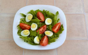 Salade de roquette, tomates, œufs de caille et truite